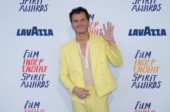 Andrew Scott poses, waving in a pastel yellow suit at the Spirit Awards
