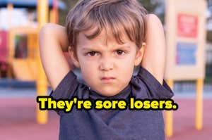 Child with hands behind head, looking annoyed, with text "They're sore losers." at a playground