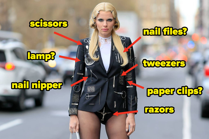 Celebrity in a black outfit embellished with oversized accessories resembling grooming tools