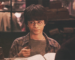Daniel Radcliffe as Harry Potter wearing round glasses, waving a wand