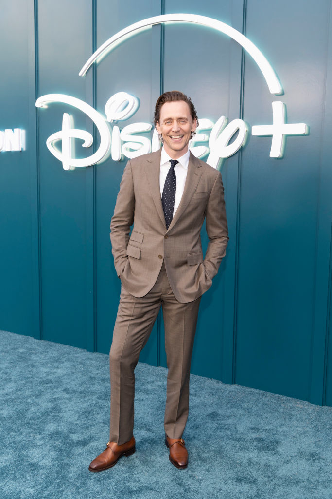 Tom Hiddleston posing in a tailored suit at a Disney+ event