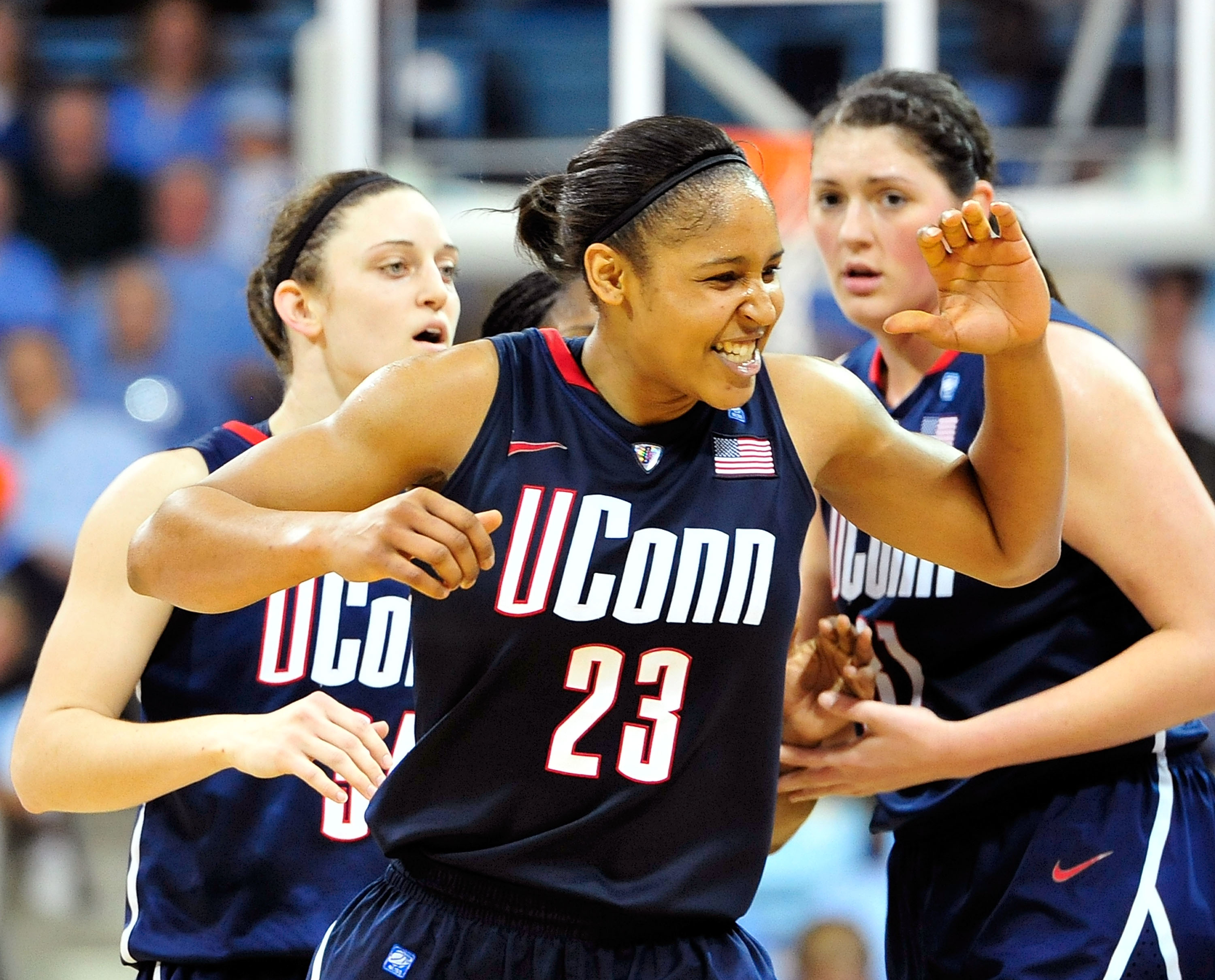 Three UConn basketball players on court celebrating, with one making an &quot;OK&quot; gesture