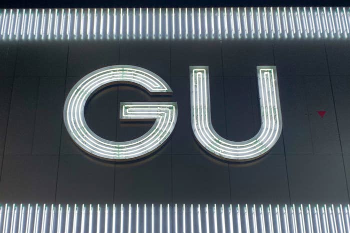 Sign with letters &quot;GU&quot; illuminated on a dark background, possibly a logo or brand identifier