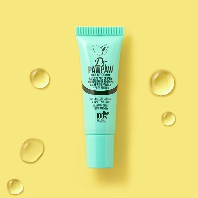 Tube of Dr. PAWPAW balm on a yellow background with product drops around it