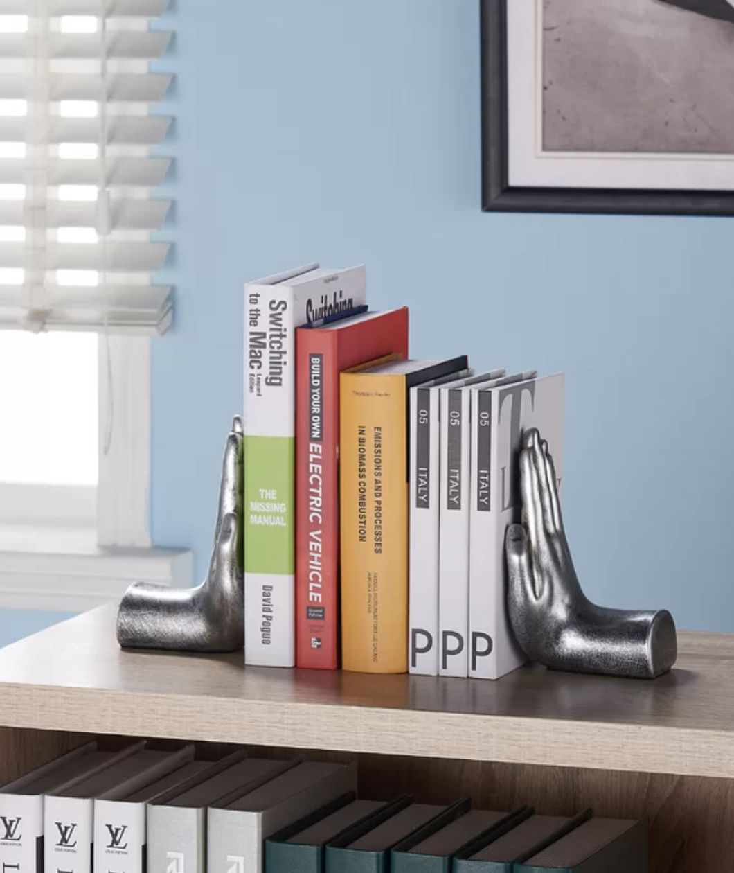 Decorative bookends shaped like hands supporting a row of books on a shelf