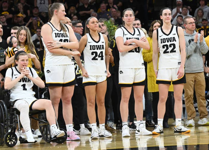 Iowa women&#x27;s basketball team in uniform on the court during a game, one player in a wheelchair