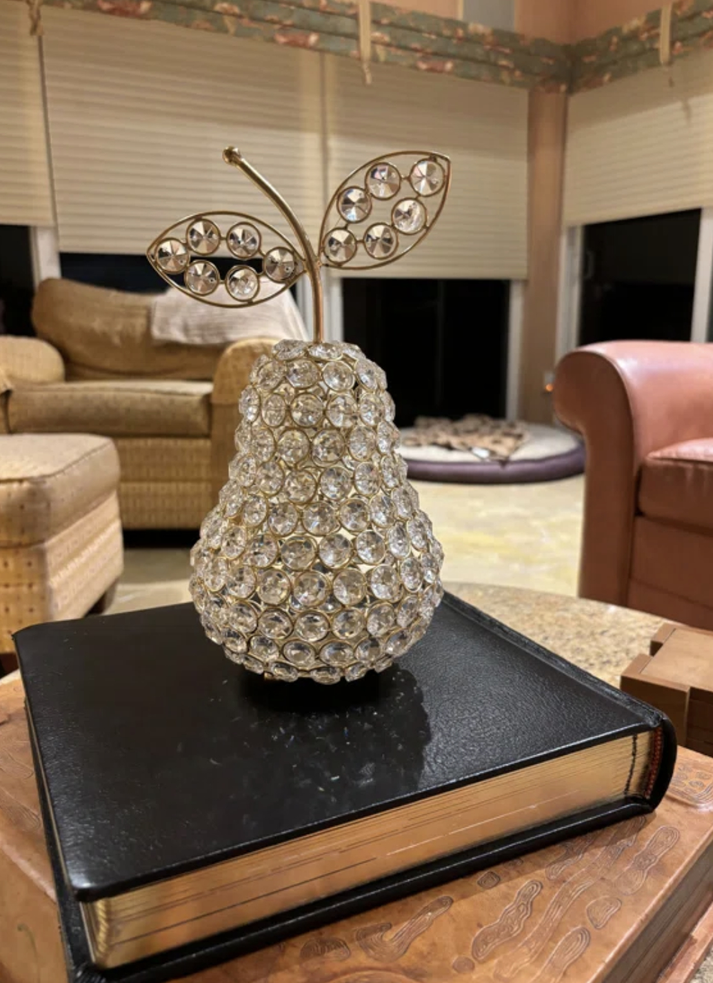 Decorative crystal pear resting on a closed book on a wooden table