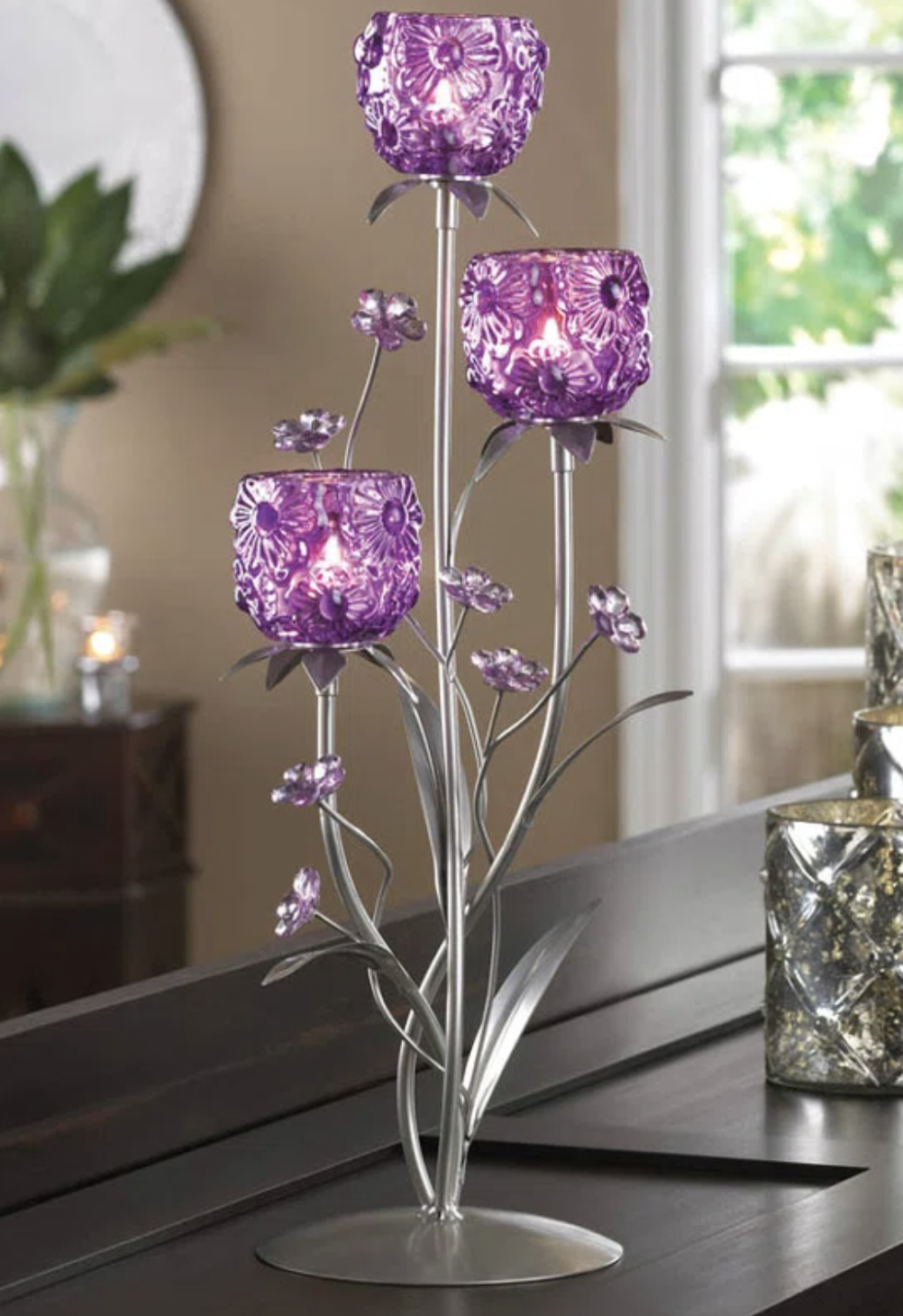 Five purple, patterned candle holders arranged on a metallic tree-like stand on a table