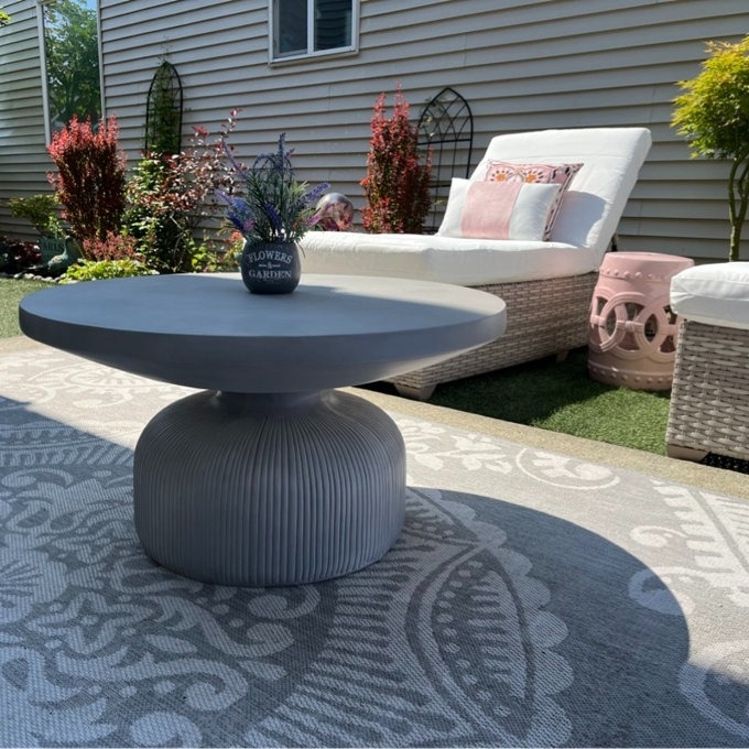 Outdoor patio setting with a coffee table, sofa, and decorative plants. No persons in image