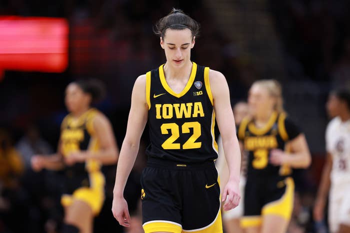 Female basketball player in Iowa uniform walking on court, focus on player #22