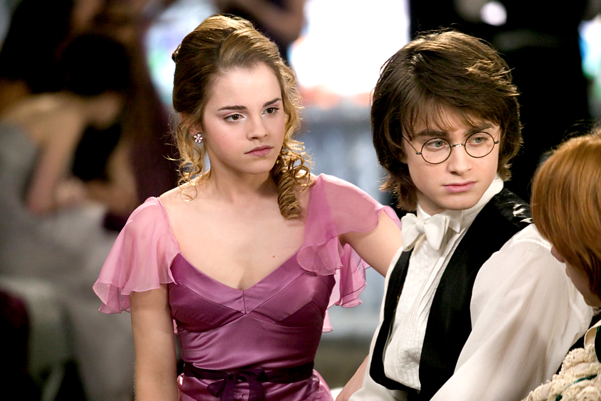 Hermione Granger in a pink dress and Harry Potter in a formal suit at a dance event