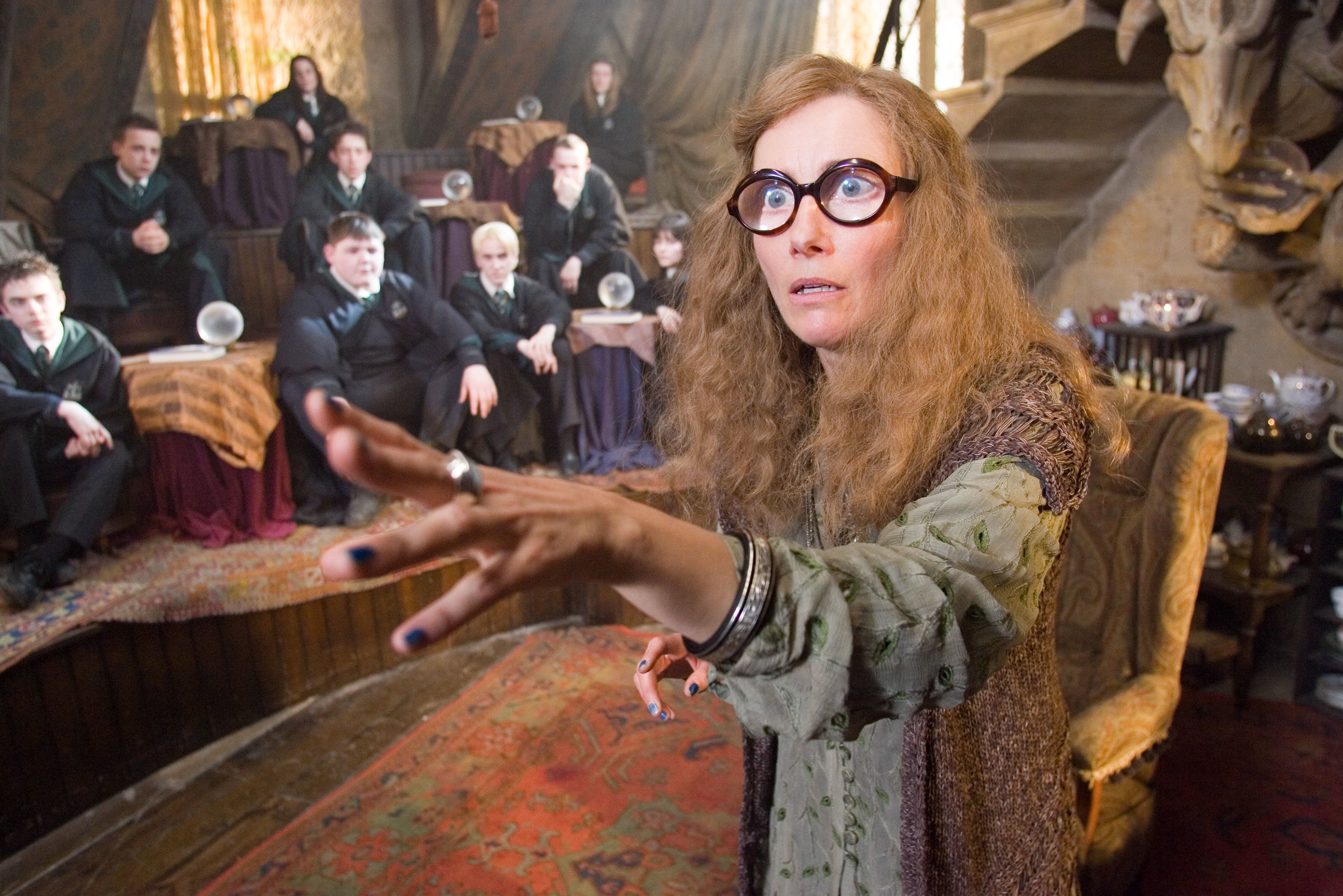 Character Sybill Trelawney in layered clothing teaching a class in the Hogwarts classroom