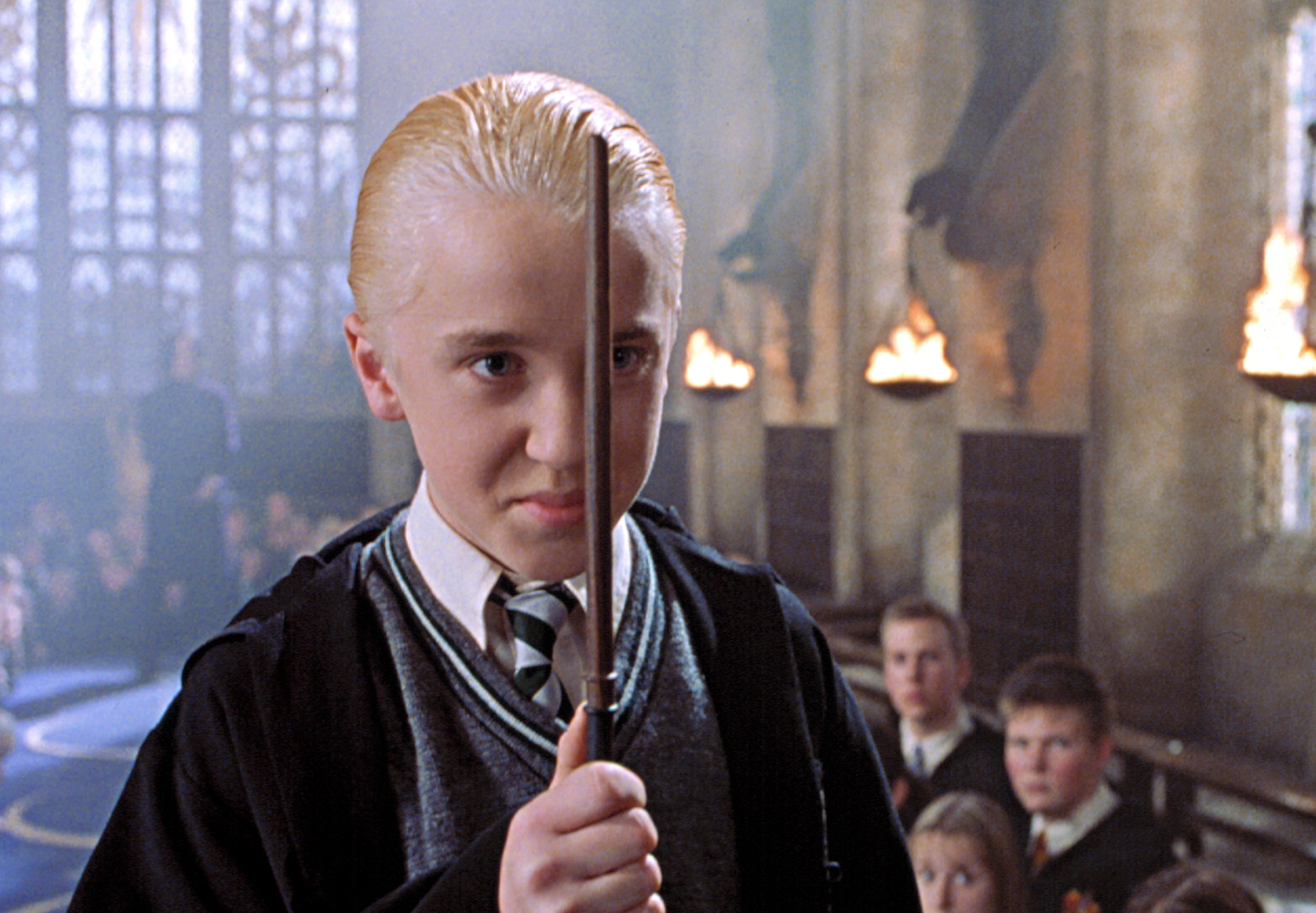 Draco Malfoy from Harry Potter, in school robes, holding a wand