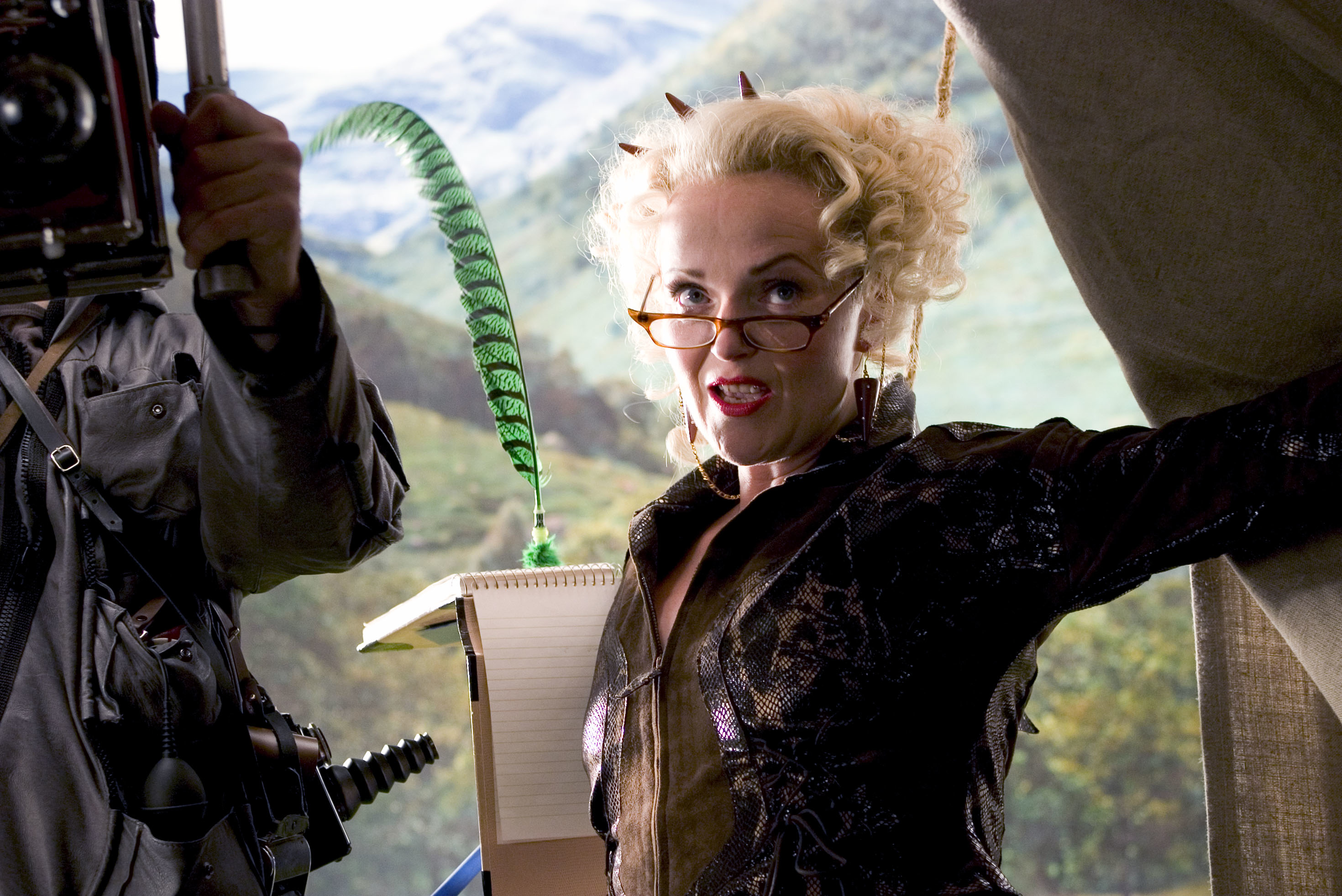 Rita Skeeter from Harry Potter films poses with a quill, wearing a patterned outfit