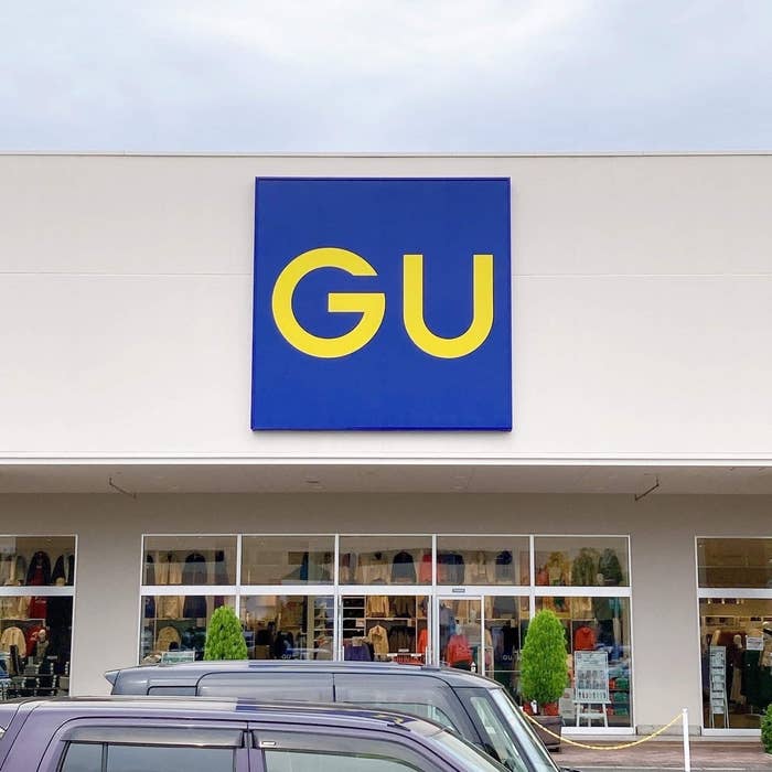 Sign of 'GU' store with large blue square and capital letters in yellow above entrance