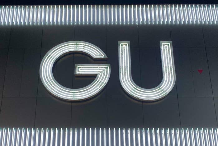 A lit-up sign with the letters &quot;GU&quot; against a dark background with linear lights above and below