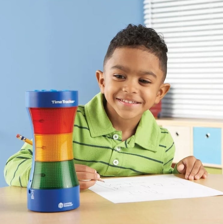 Smiling child at a desk with a Time Tracker visual timer used to teach time management