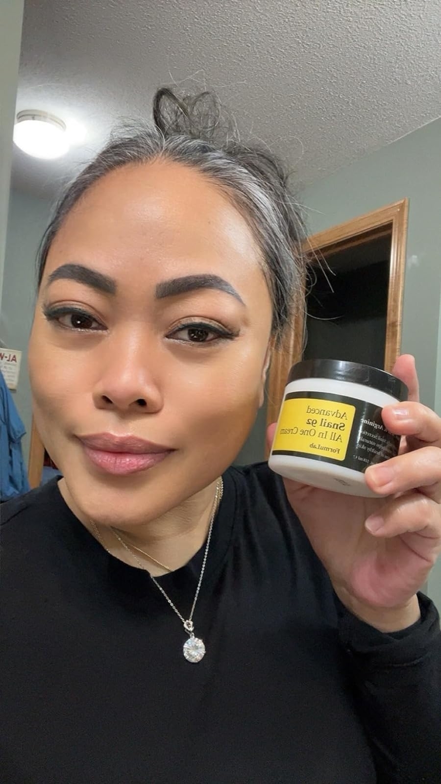 Woman holding a jar of the snail mucin face cream with visibly smooth and hydrated skin