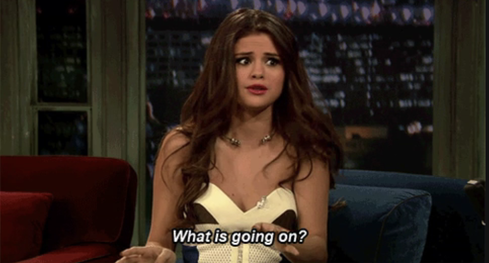 Selena Gomez sitting on a couch looking confused with the caption &quot;What is going on?&quot;