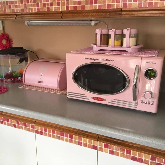 Retro-style pink kitchen appliances, including a pink microwave and bread bin, displayed on a countertop