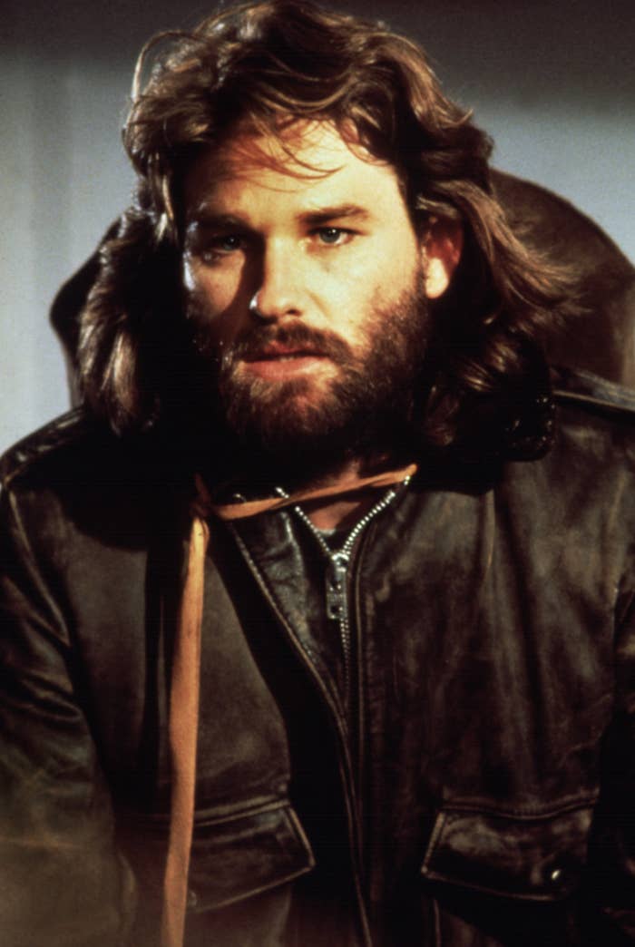 Kurt Russell in costume as R.J. MacReady from the film "The Thing," wearing a brown leather jacket with fur collar