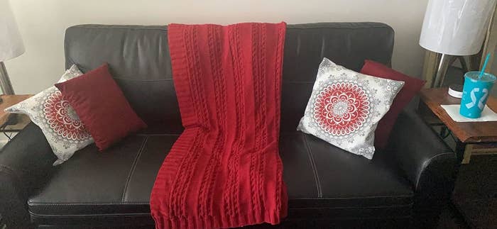 Red throw blanket on a couch with patterned pillows