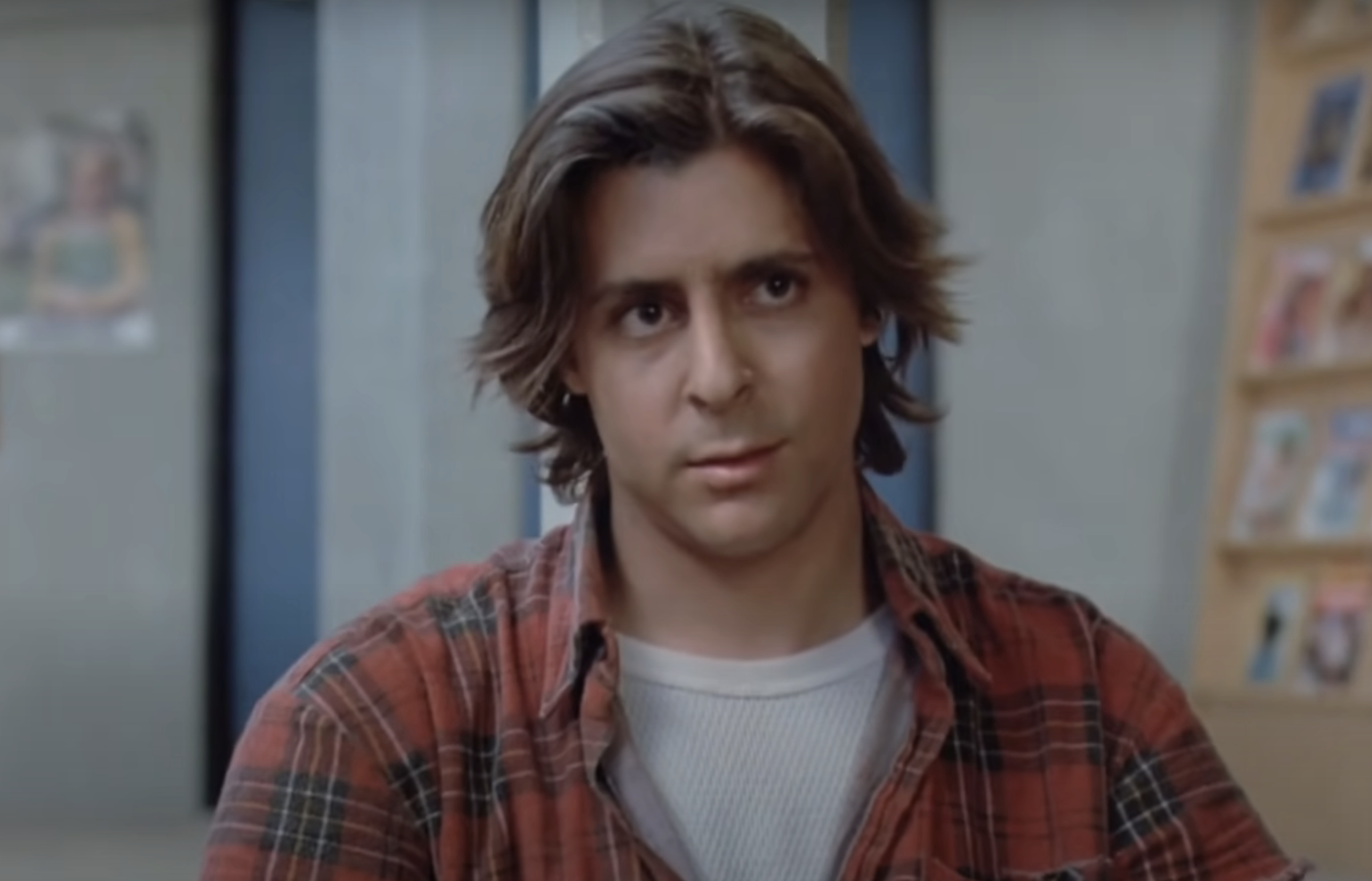 John Bender from The Breakfast Club wearing a plaid shirt, looking forward with a slight frown