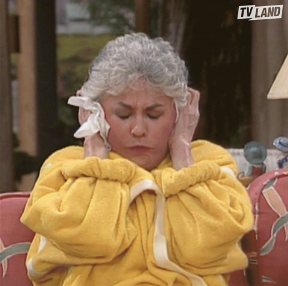 Character from &quot;The Golden Girls&quot; wearing a bathrobe, looking annoyed with hands on ears