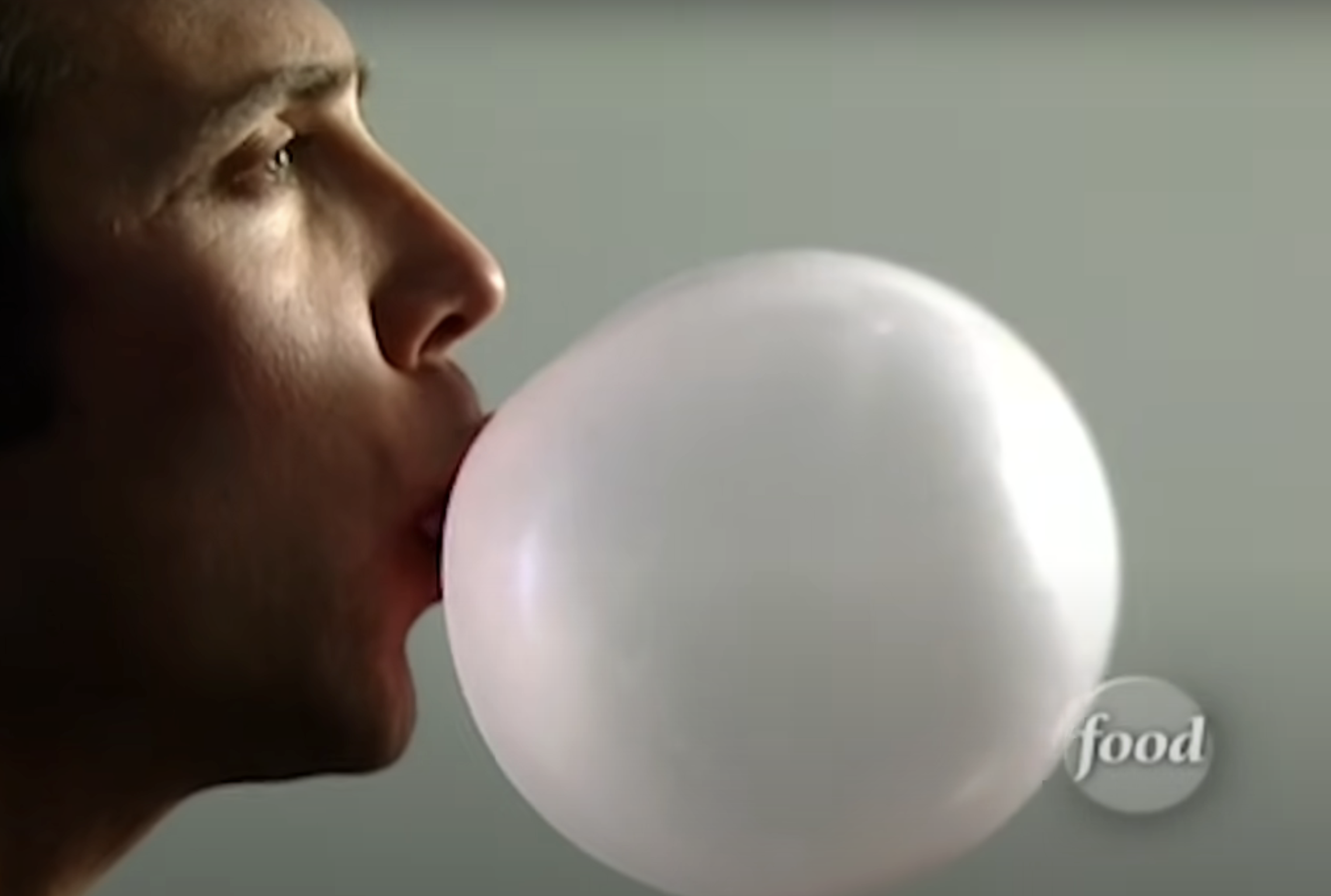 Person blowing a large bubble with chewing gum