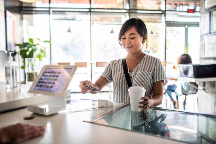 Person receiving a cup from a barista at a coffee shop counter
