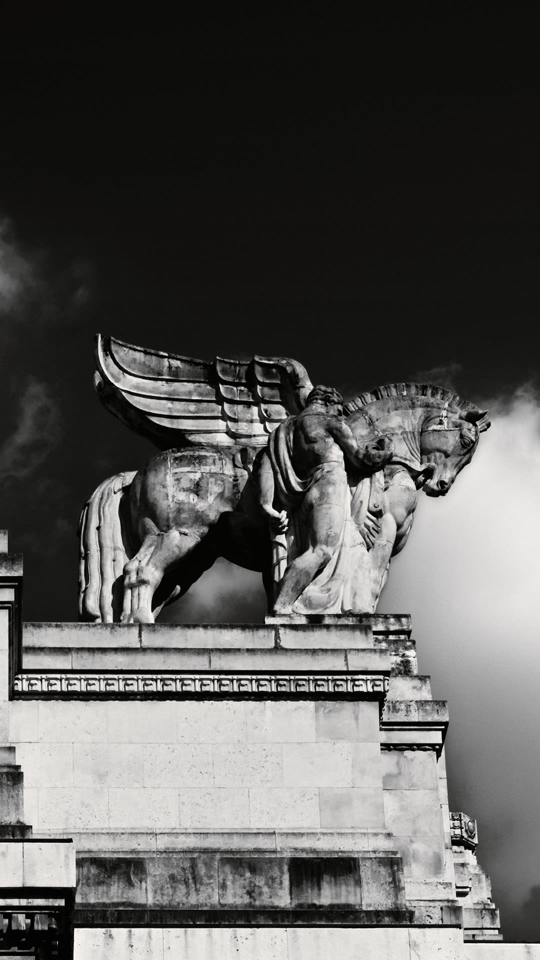 Stone sculpture of a winged lion on a building against the sky