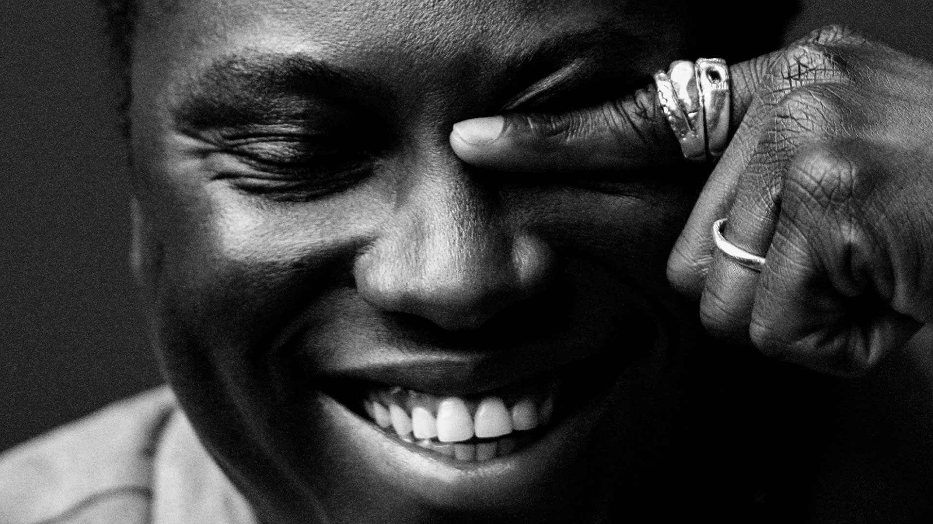Close-up of a person smiling with another&#x27;s hand gently resting on their face, showcasing a ring
