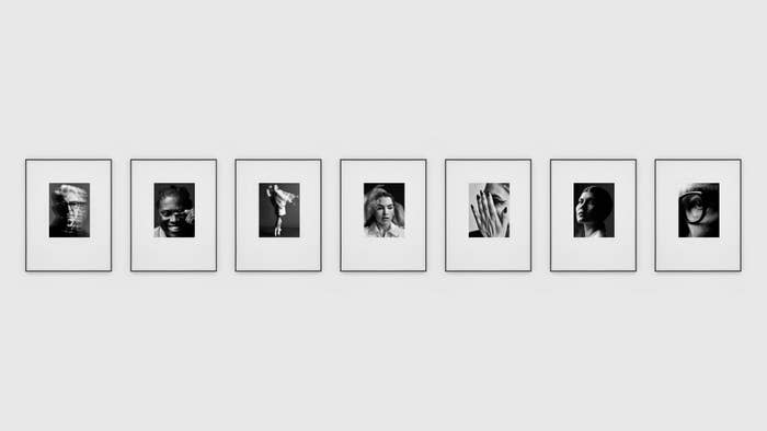 Six framed black and white photographs displayed in a row on a gallery wall