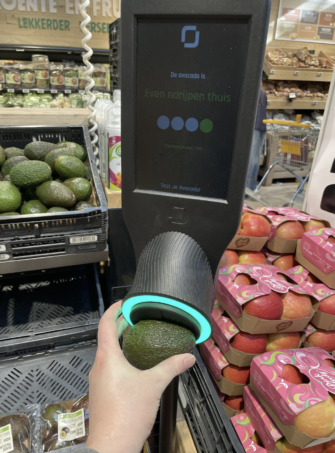 Person using an avocado ripeness tester machine at a grocery store