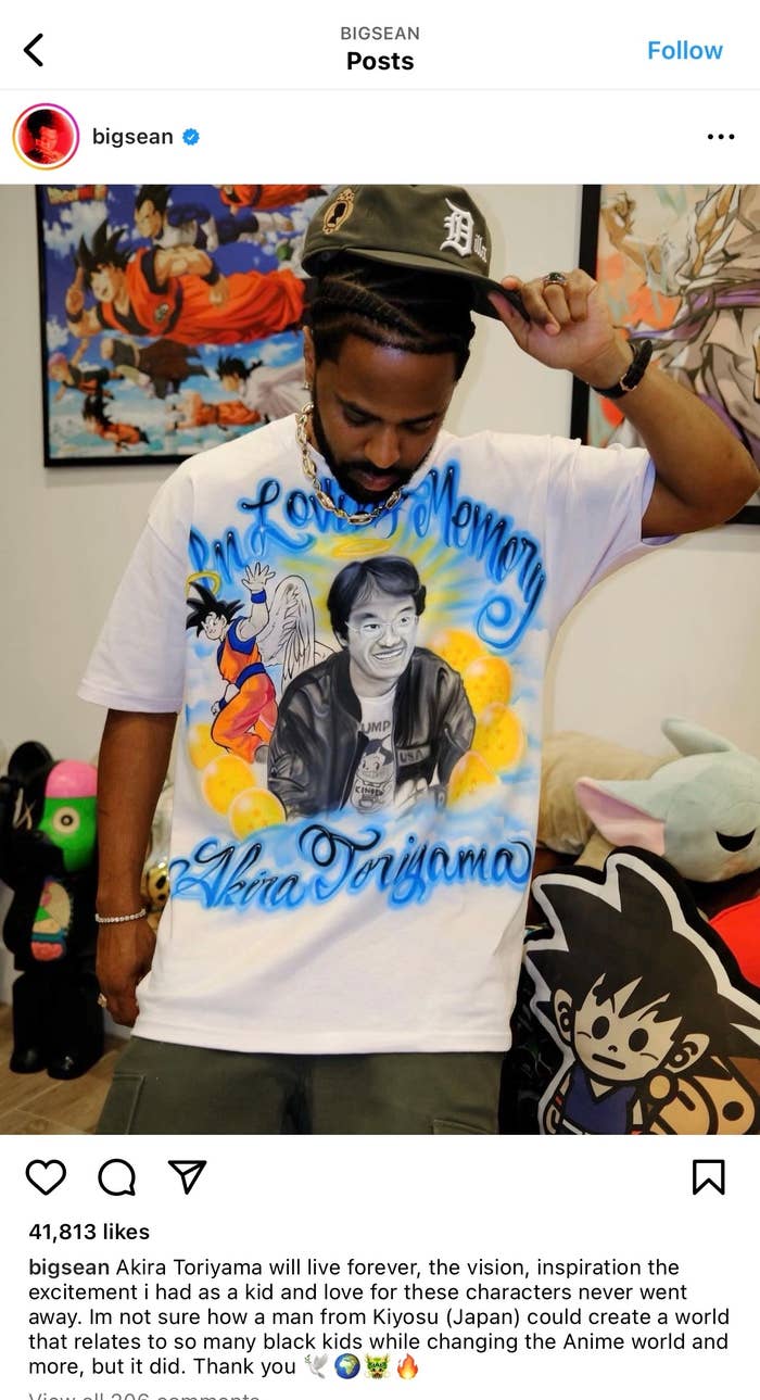 Man in a white &#x27;In Loving Memory&#x27; tribute T-shirt with anime character design, standing in front of plush toys