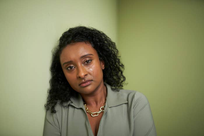 Woman with curly hair wearing a chain necklace and a shirt with buttons