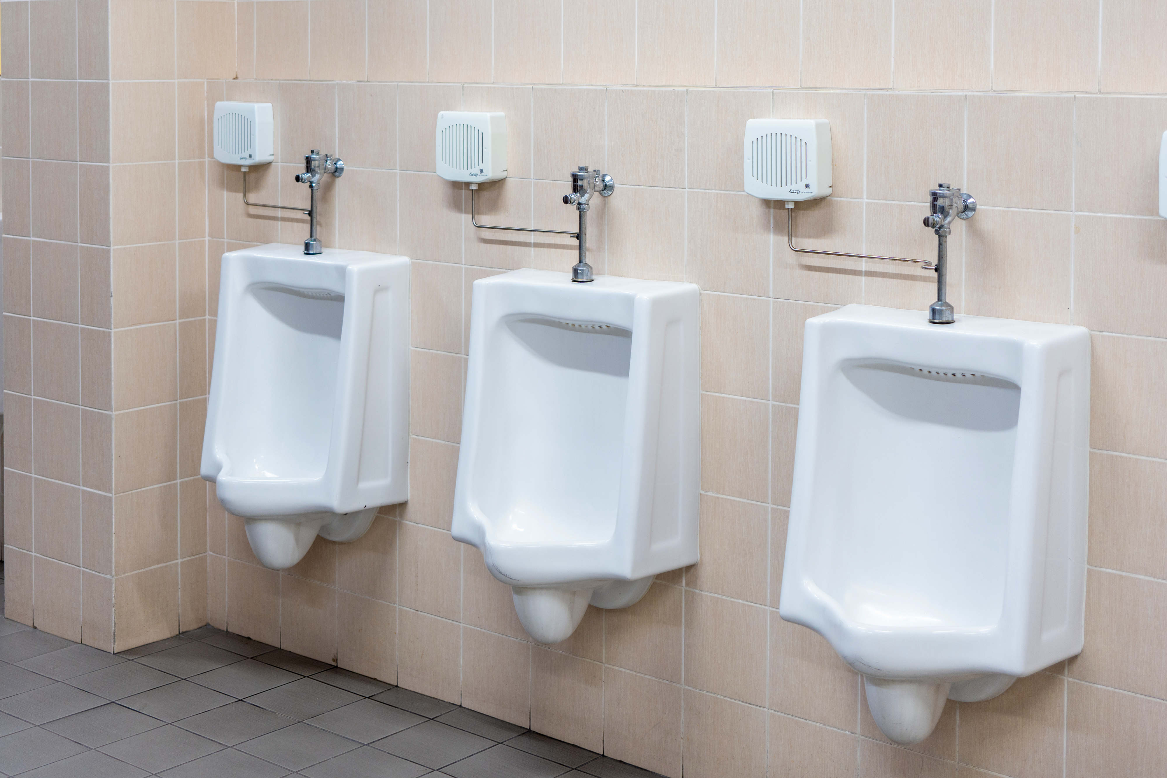 Three urinals mounted on a tiled wall in a restroom
