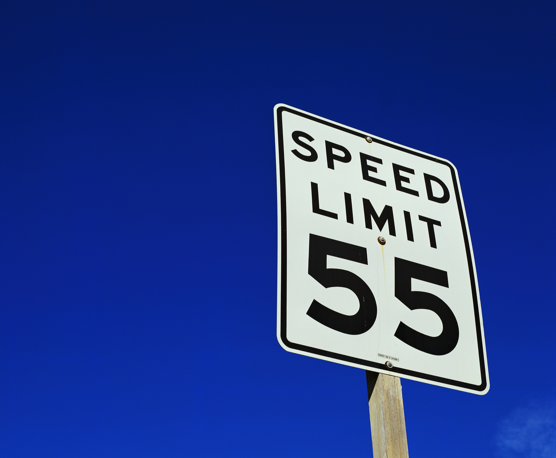 A speed limit sign showing &quot;55&quot; against a clear sky
