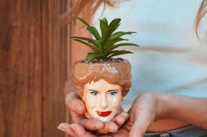 Person holding small planter shaped like blanche from golden girls with faux plant