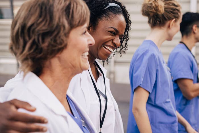 Group of smiling healthcare workers, one with a stethoscope, sharing a joyful moment