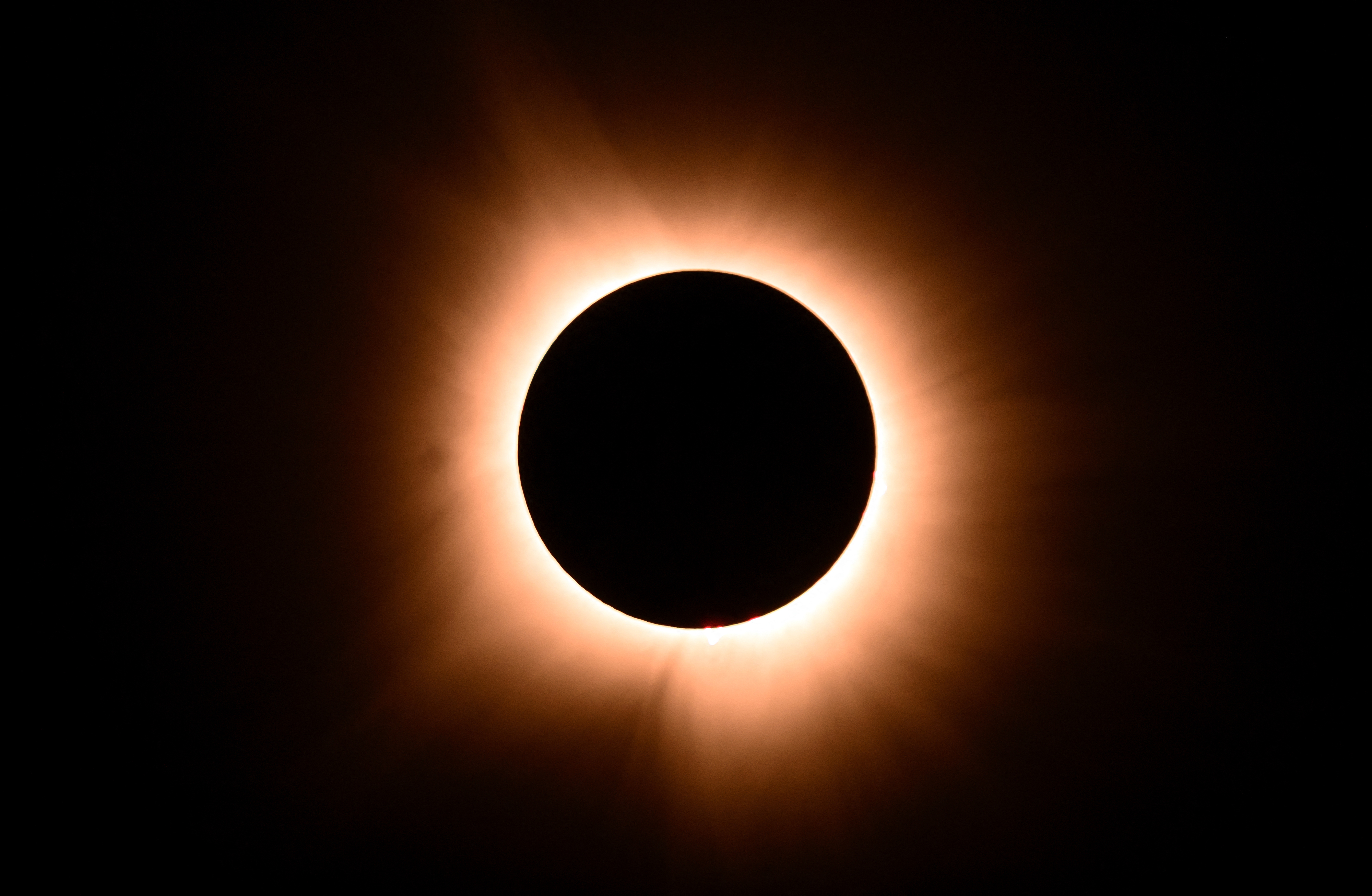 Solar eclipse with the moon covering the sun, creating a glowing corona