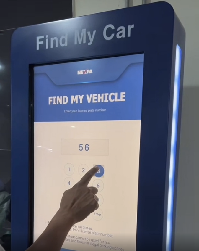 Interactive kiosk screen with &quot;Find My Vehicle&quot; feature engaged, a finger entering a license plate number