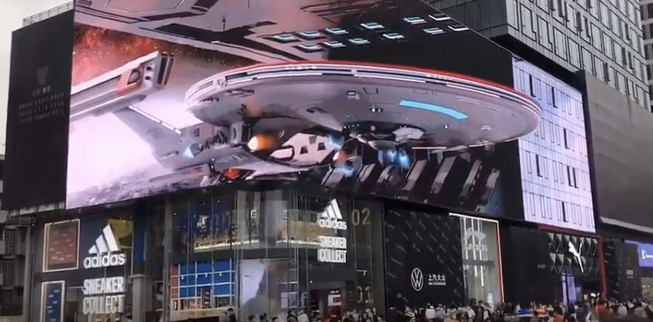Billboard displays a Star Trek spaceship above an urban street with buildings and stores