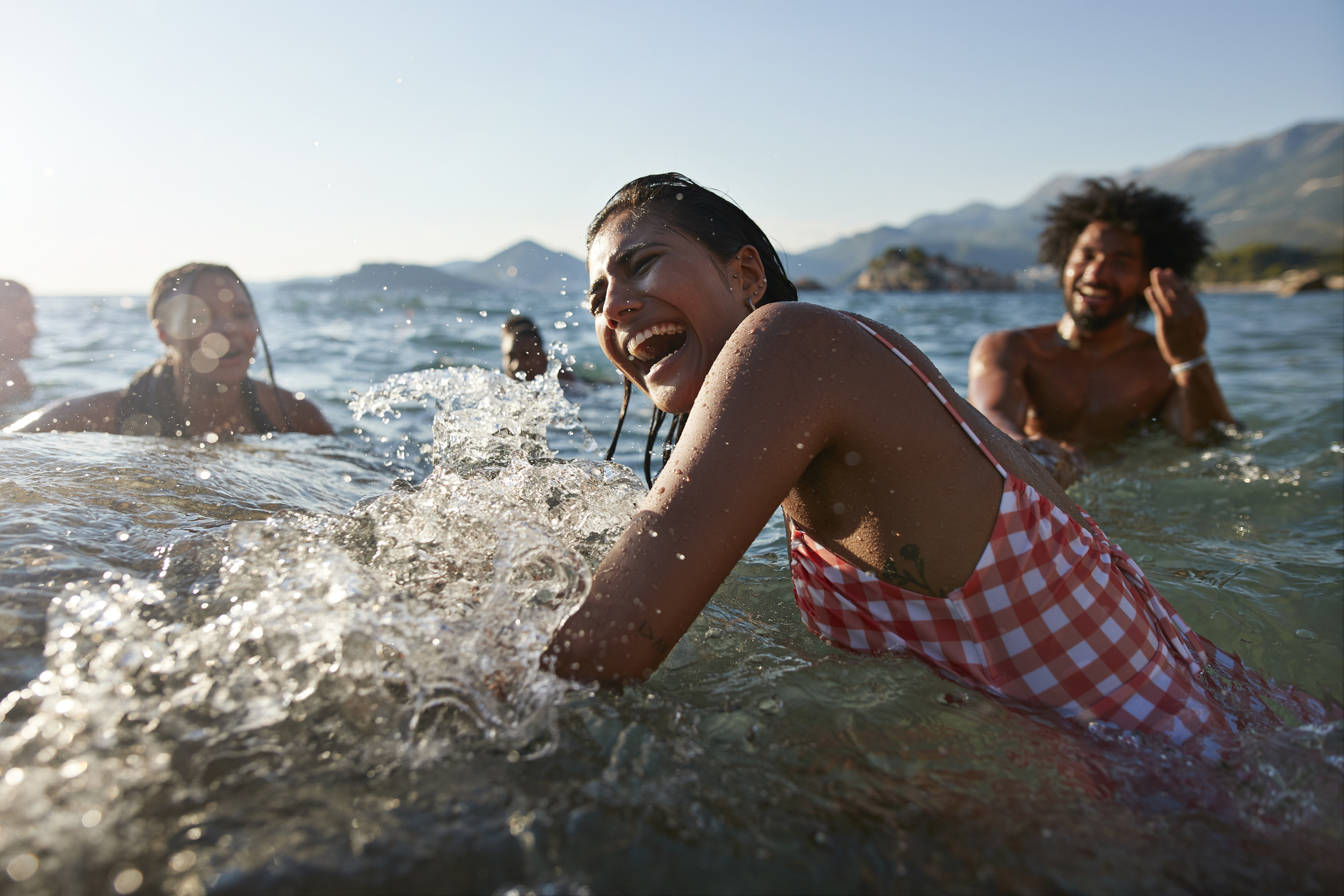 Group of friends laughing and splashing in the sea