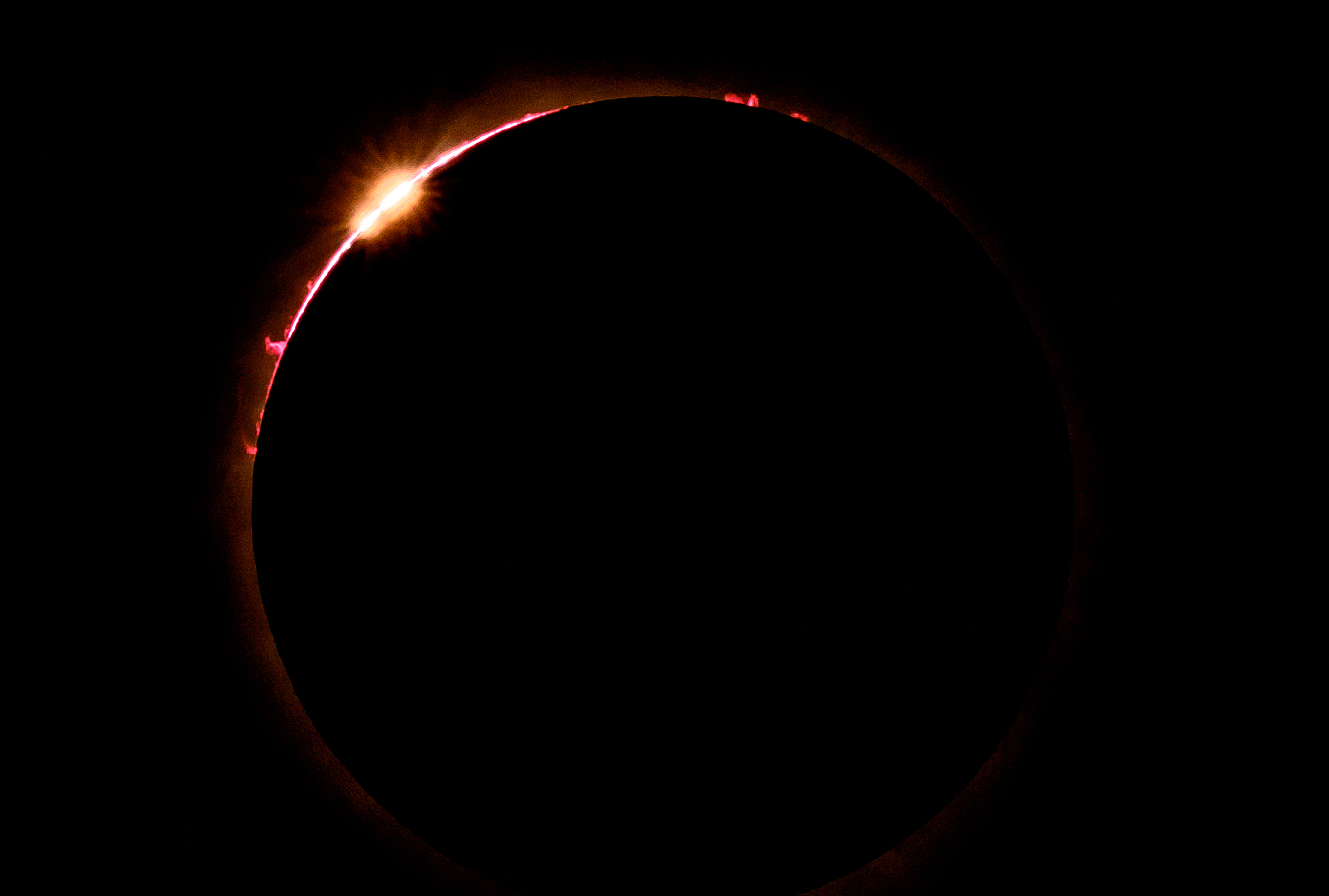 A solar eclipse showing the sun&#x27;s corona and a bright prominence
