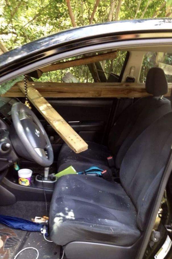 A wooden beam impales a car&#x27;s windshield and front seat, with debris on the dashboard