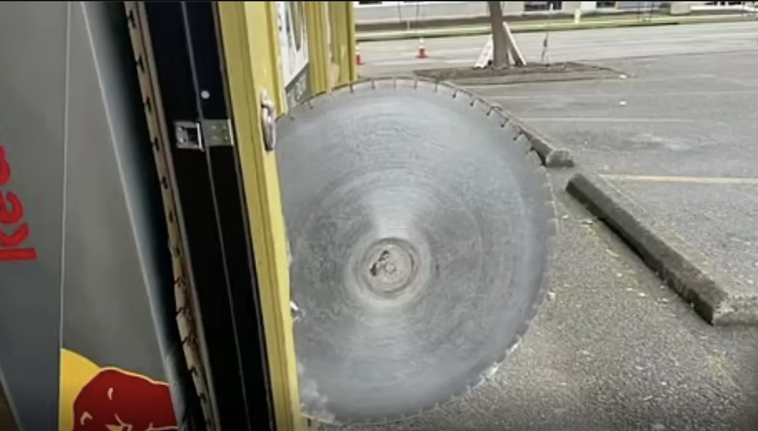 Large circular saw blade leaning against vending machine outdoors