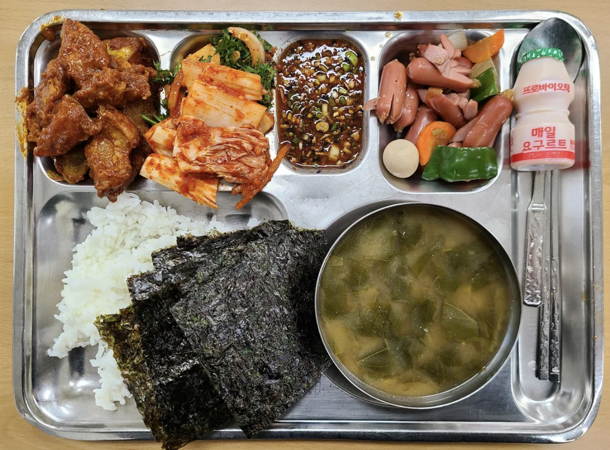 Korean meal on a tray with rice, soup, kimchi, meats, and side dishes
