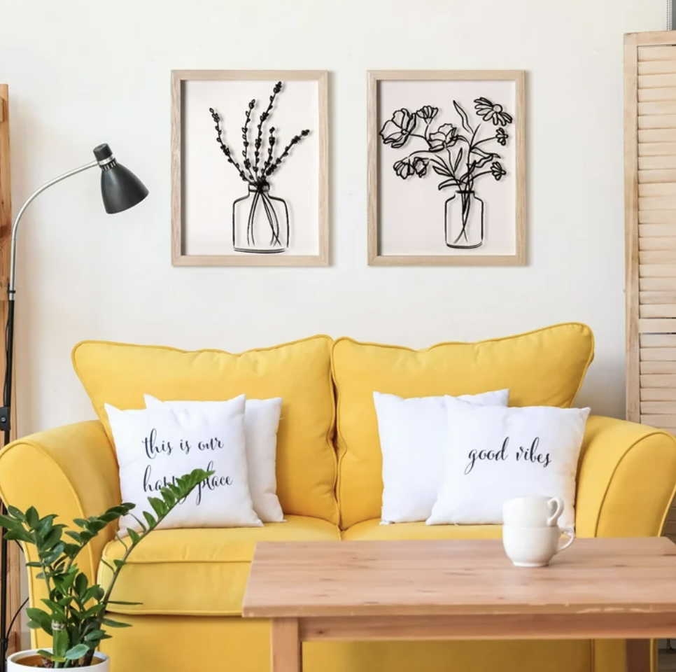 Two floral framed pictures above a yellow couch