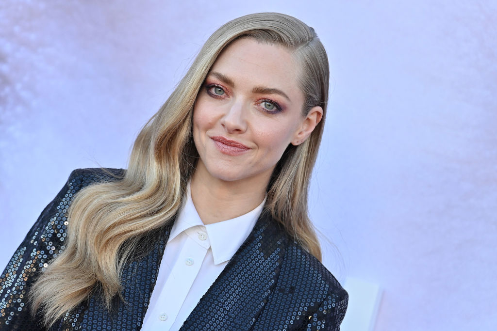 Amanda Seyfried in a sequined blazer and white shirt, smiling at a press event